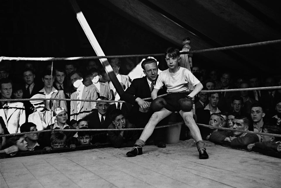 A boxing instructor coaches his young pupil in the Hughes of London boxing pavilion at a Lancashire fair. Original Publication: Picture Post - 2046 - Where Champions Are Born - pub. 1945 (Photo by Francis Reiss/Getty Images)