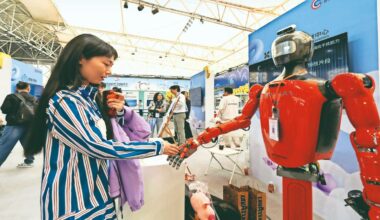 File image of a woman interacting with a humanoid robot during an AI developer conference in Wuhan, China. Even as we become more digitally interconnected, geopolitical rivalries remain fierce, often intensified by the very technologies that claim to transcend them. Photo credit: Bloomberg