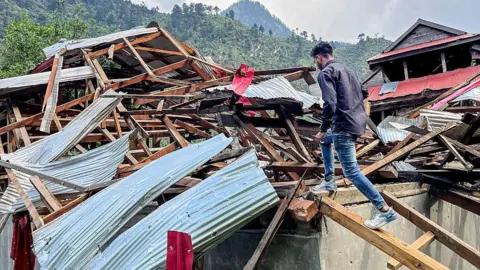 Getty Images A man inspects his damaged house in Neelum Valley in Pakistan-administered Kashmir