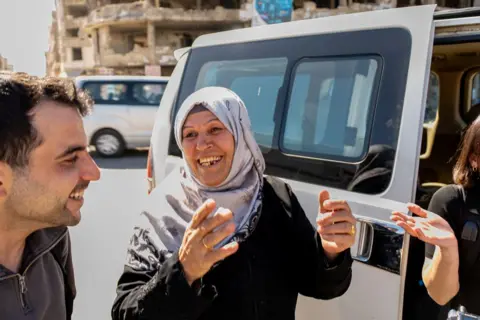 Rolf Andreason/BBC Fatima Hazzouri  stands outside a mini-van