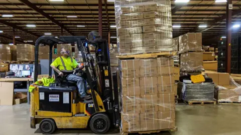 Getty Images A person in a yellow reflective vest mans a forklift piled high with boxes of toys at the Duncan Toy Company in the firm's warehouse in Columbus, Indiana, on April 16, 2025. 