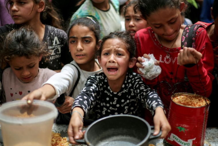 Des enfants palestiniens attendent de recevoir un repas chaud dans une cuisine caritative à Gaza-ville, le 30 avril 2025 ( AFP / Eyad BABA )