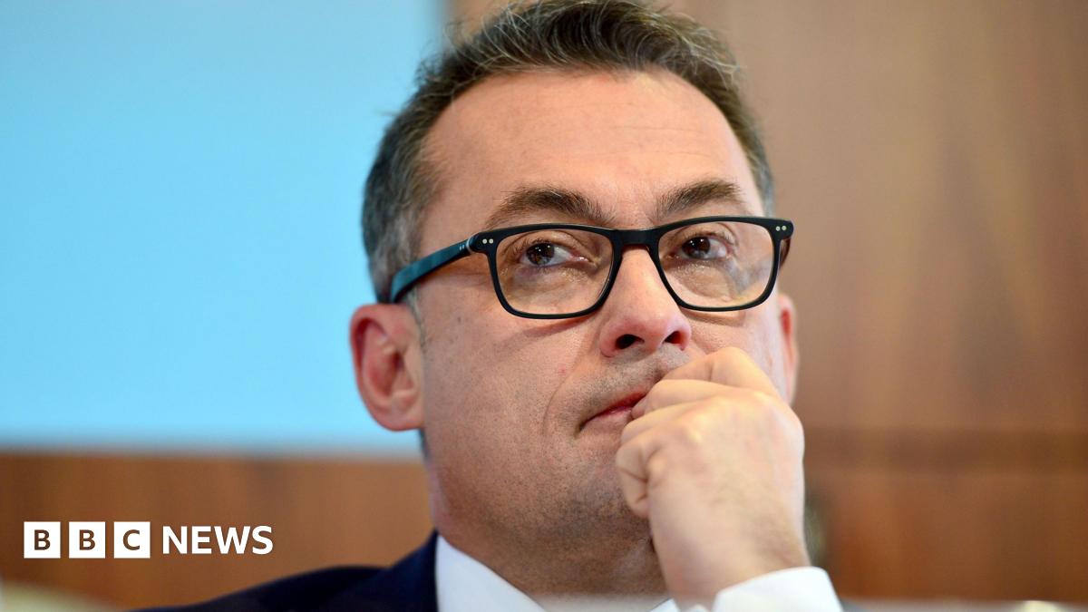 Joachim Nagel wearing glasses and holding his hand to his mouth pensively