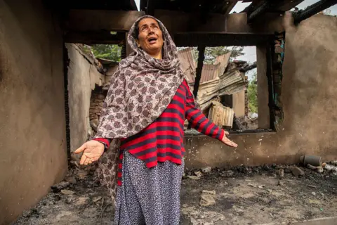 Getty Images A Kashmiri woman stands inside her shell-damaged home in Salamabad, near the LoC in Uri