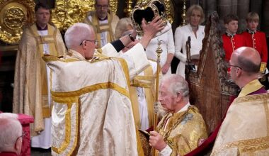 The archbishop very carefully places the crown on Charles's head