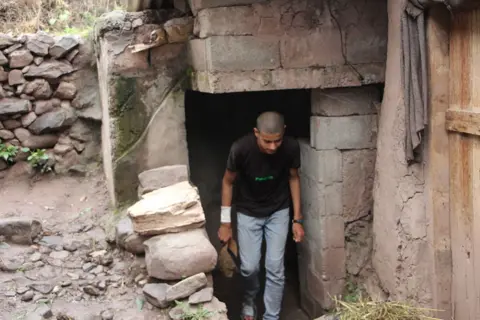 Getty Images A resident of Bakoat village walks through the entrance of a bunker prepared for protection from cross-border fire