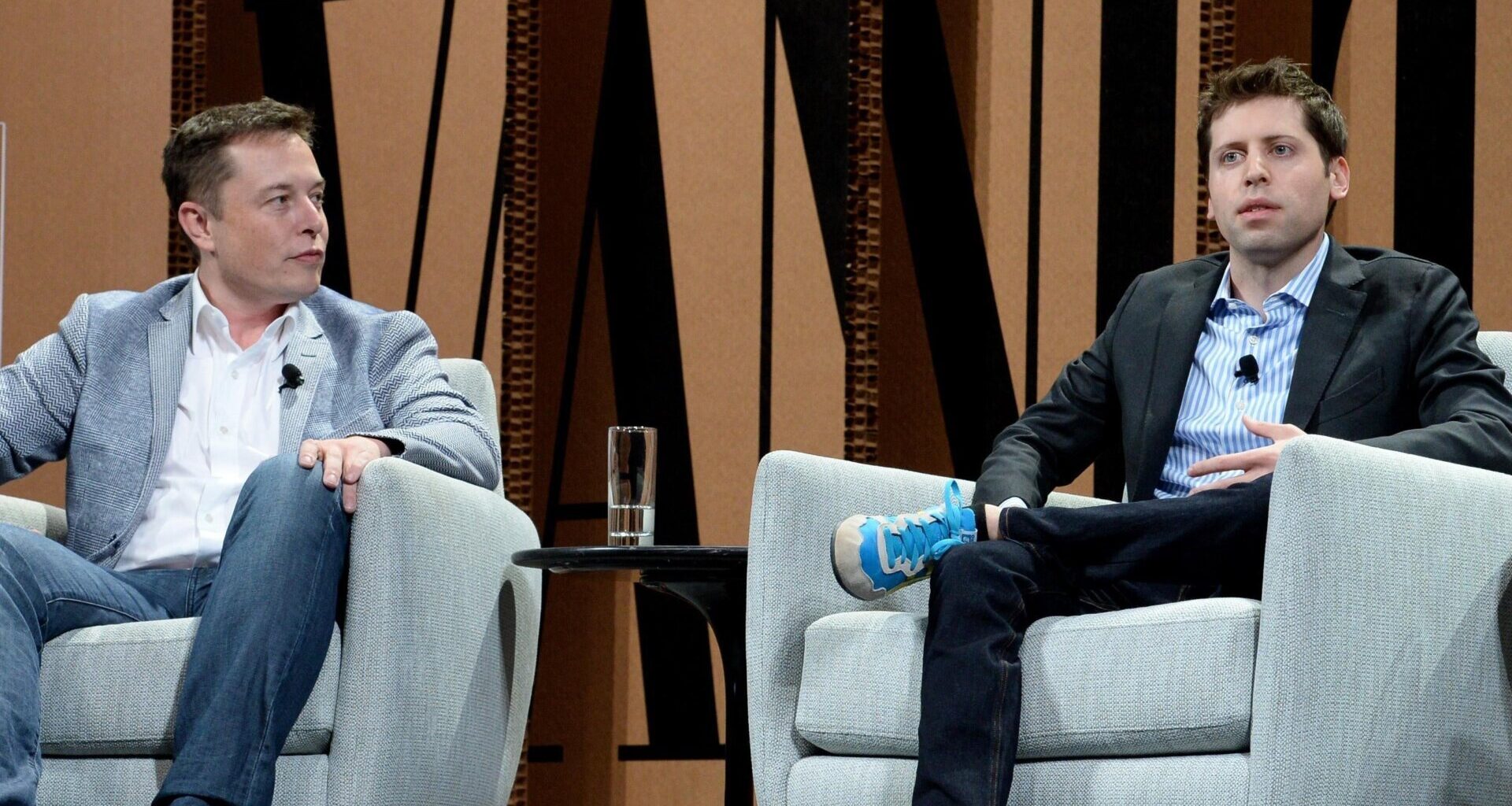 Elon Musk and Sam Altman sit in chairs on stage