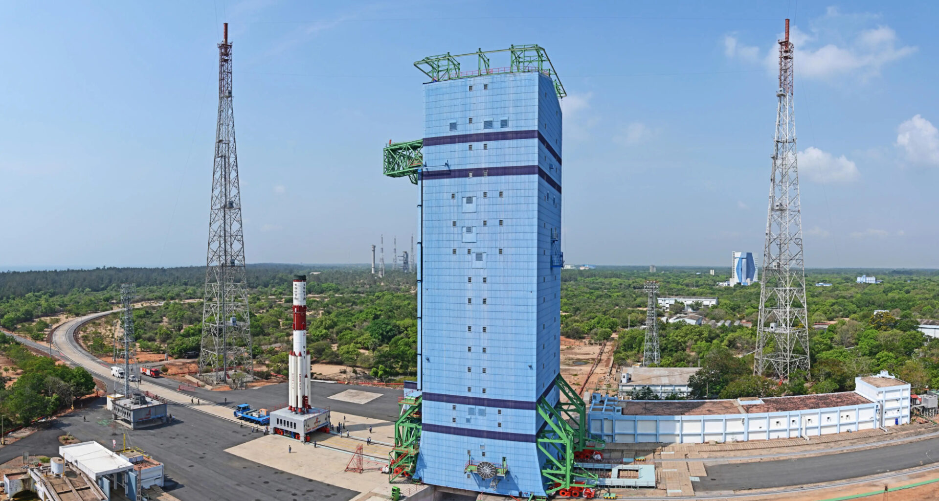 a white and red rocket rolls out to a blue servicing tower in this long-distance image
