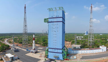 a white and red rocket rolls out to a blue servicing tower in this long-distance image