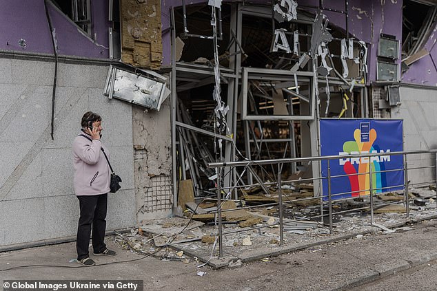 A Russian drone attack overnight on the Ukrainian capital, Kyiv, wounded 11 people, Ukraine's State Emergency Service said on Sunday. Pictured: A woman talks on the phone while standing at the entrance to the Dream Town shopping mall in the Obolonskyi district damaged by a Russian drone strike on May 4
