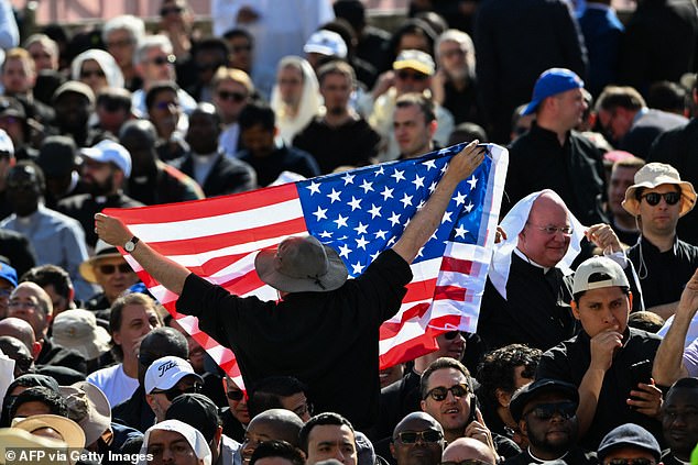 A US flag is held up by a man ahead a Holy Mass for the Beginning of the Pontificate of Pope Leo XIV