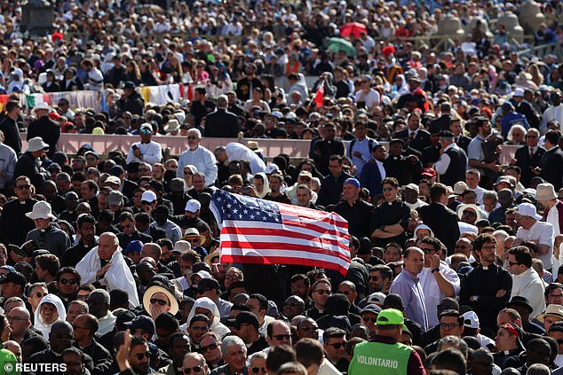 A faithful holds up a U.S. flag at the Saint Peter's Square, on the day Pope Leo XIV holds his inaugural Mass