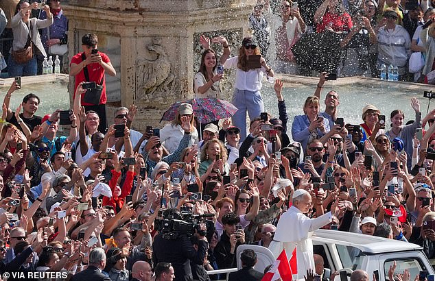 People in the crowd hold up their phones to take photos of Pope Leo XIV as he tours through the piazza