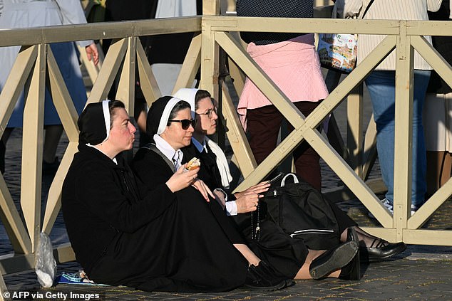 Nuns sit on the ground and eat ahead of Pope Leo XIV arriving at St Peter's Square -- May 18, 2025