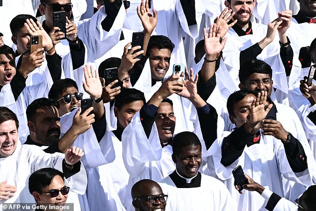 Priests wave and cheer and hold up their mobile phones to get a snapshot of history inside St Peter's Square, Vatican City