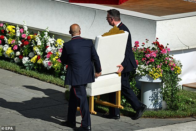 Vatican officials carry the chair of Pope Leo XIV ahead of the inauguration mass
