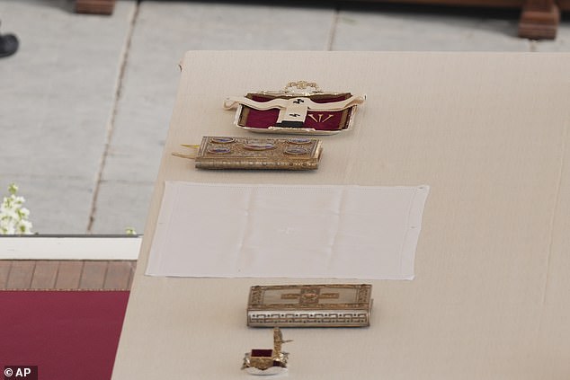 The pallium, or lambswool stole, centre, and the fisherman's ring, bottom, symbols of the papacy, are seen on the altar