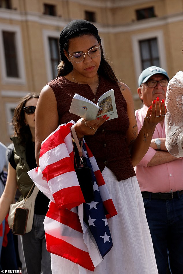 A woman reads a book during Pope Leo XIV's inaugural mass at the Vatican