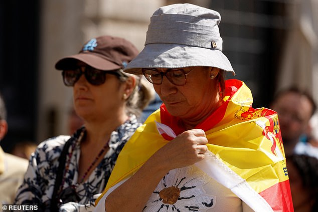 A person is wrapped in a Spanish flag as they attend Pope Leo XIV's inaugural mass
