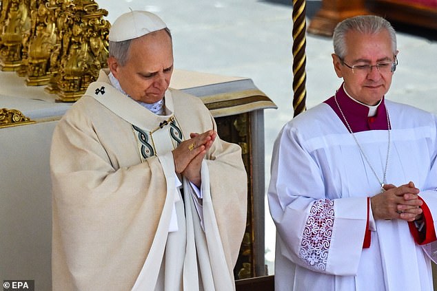 Pope Leo XIV looks at the Ring of the Fisherman after it was placed on his finger. He turned his hand to look at the ring and seal and then clasped his hands in front of him in prayer