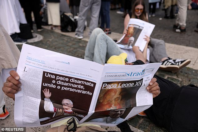 A person reads a newspaper with an image of Pope Leo XIV, on the day Pope Leo XIV holds his inaugural mass