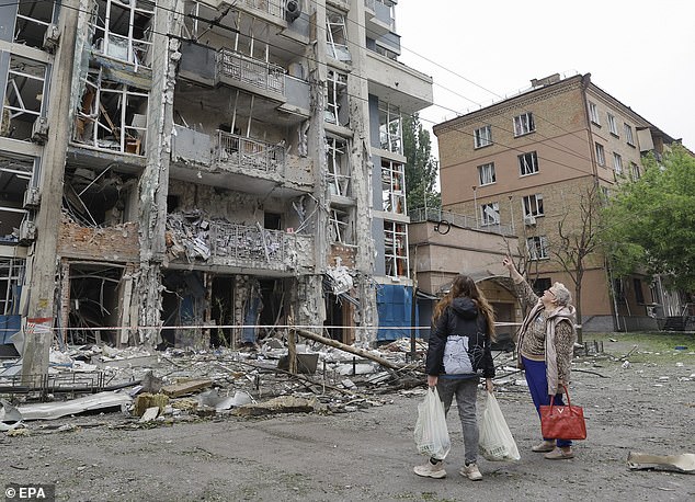 People look at a residential building struck by a drone following an overnight strike in Kyiv