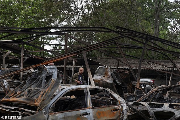 An Odesa resident stands next to cars destroyed in a residential area during a Russian drone strike