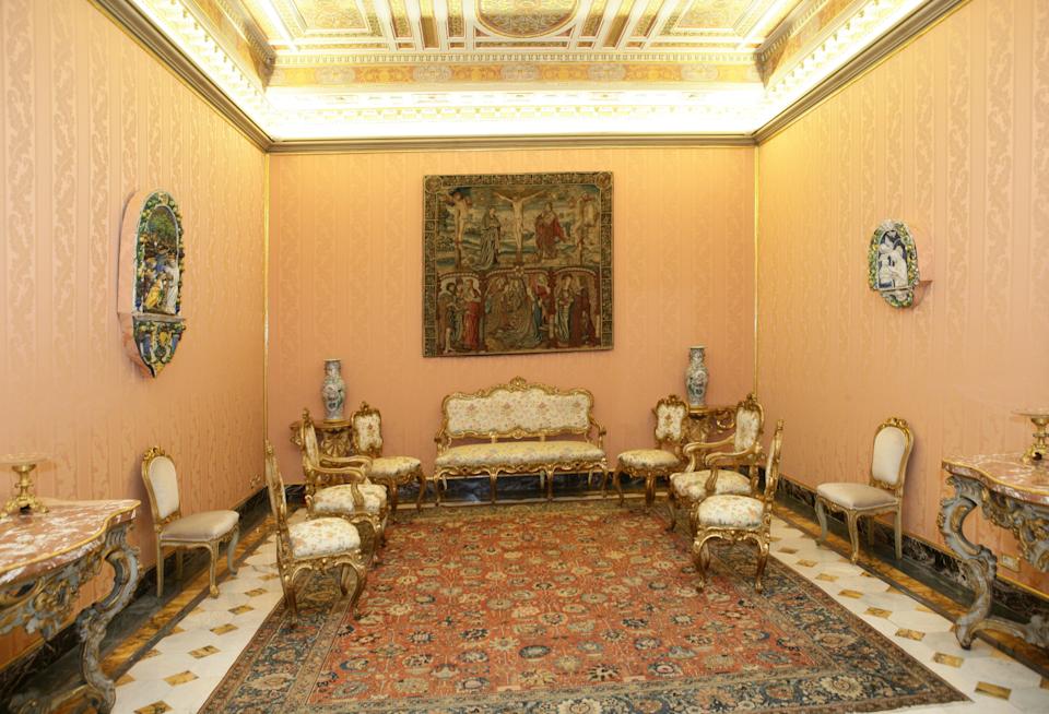 A room with yellow walls, an ornate ceiling, and antique furniture