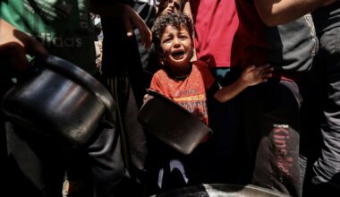 Un enfant pleure au milieu de Palestiniens qui attendent de recevoir un repas chaud distribué par une association caritative locale à Nousseirat, dans le centre de la bande de Gaza, le 24 mai 2025 (Eyad BABA)
