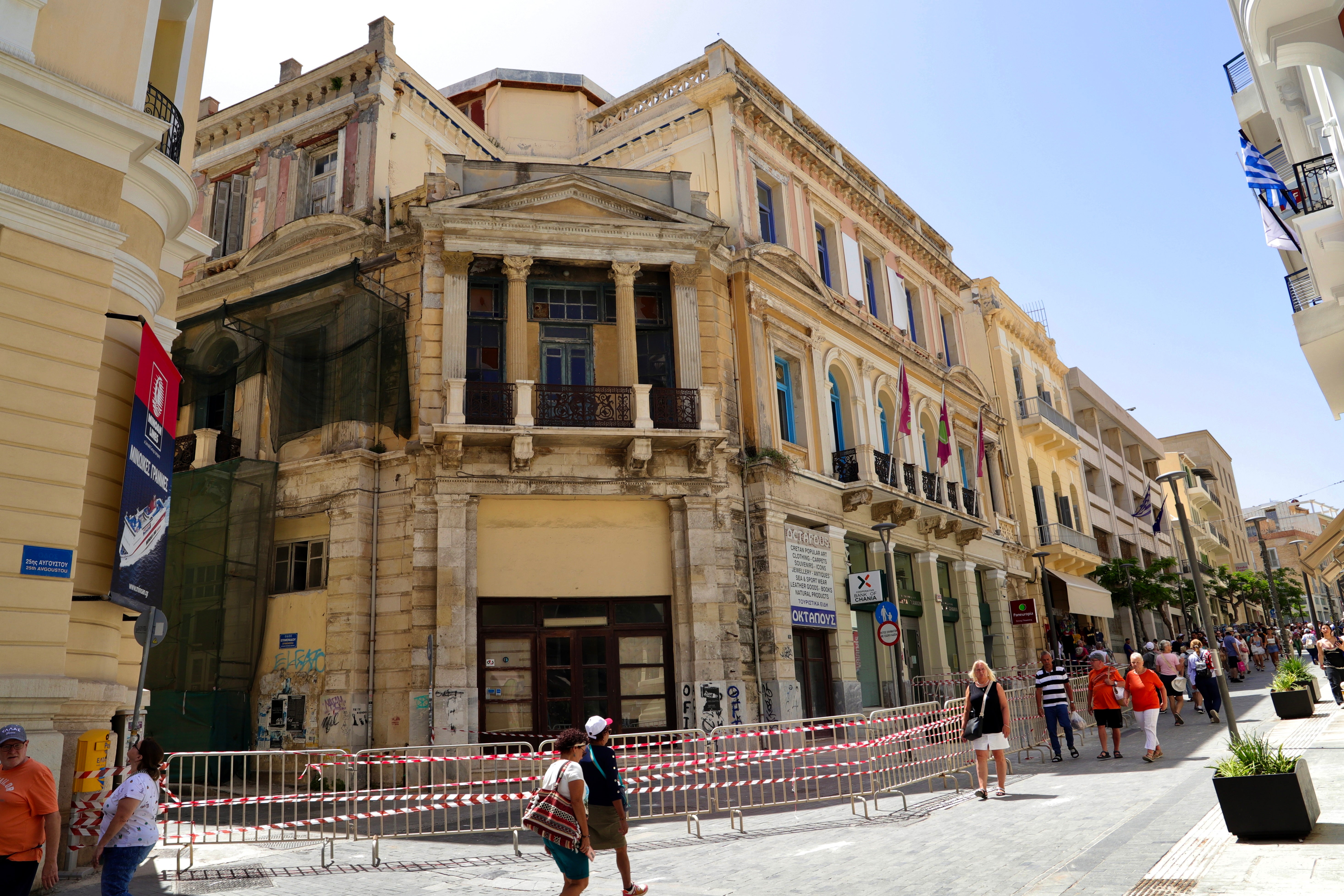 Tourists walk past a cordoned area with old buildings after an earthquake shook Heraklion in Crete
