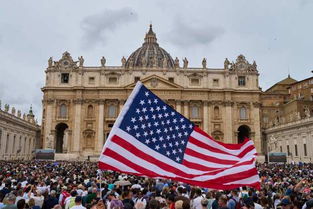 A flag from the United States waves in the crowd as Pope Leo XIV appears at the central balcony of St. Peter's Basilica for his first Sunday blessing after his election, in St. Peter's Square at the Vatican.