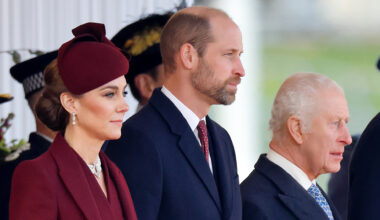 Kate Middleton wears a burgundy coat and matching hat, Prince William wears a navy coat and red tie, and King Charles wears a navy coat with a white shirt and blue tie