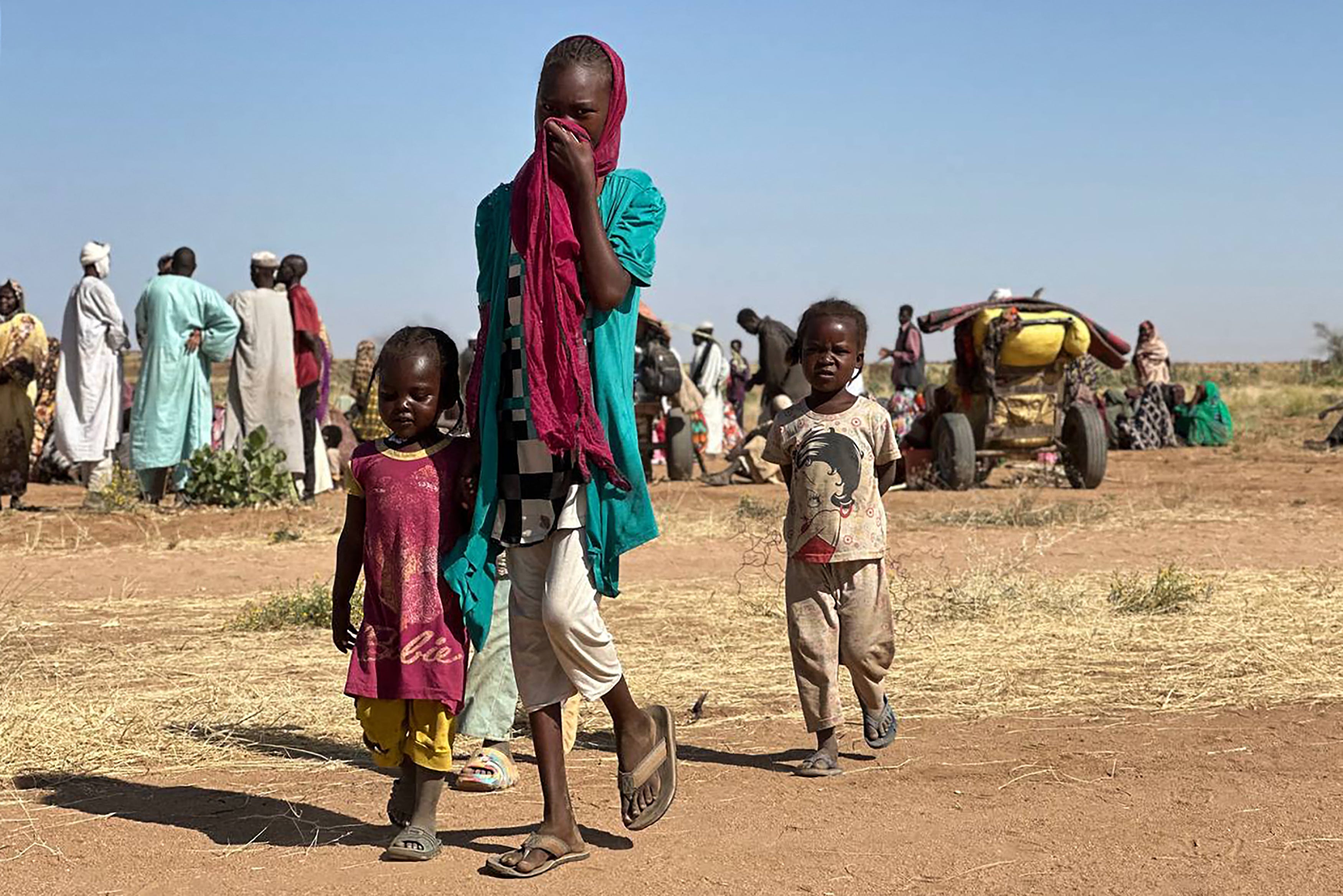 A displaced Sudanese woman, accompanied by children, walks at a camp near the town of Tawila in North Darfur in February, amid the ongoing war between the army and paramilitary forces