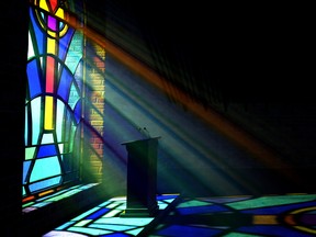 Pulpit at the front of a church below stained-glass window