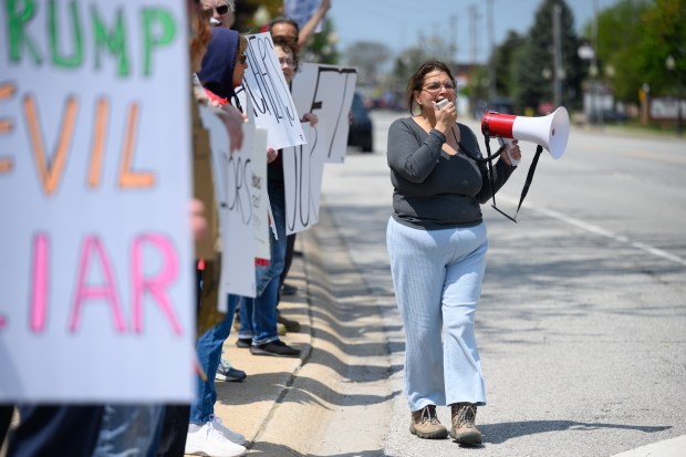 Protest organizer and NWI Takes Action co-administrator Tracie Martin, on right, leads a chant outside of a Munster Chamber of Commerce meeting featuring Indiana Governor Mike Braun as speaker on Thursday, May 8, 2025. (Kyle Telechan/for the Post-Tribune)