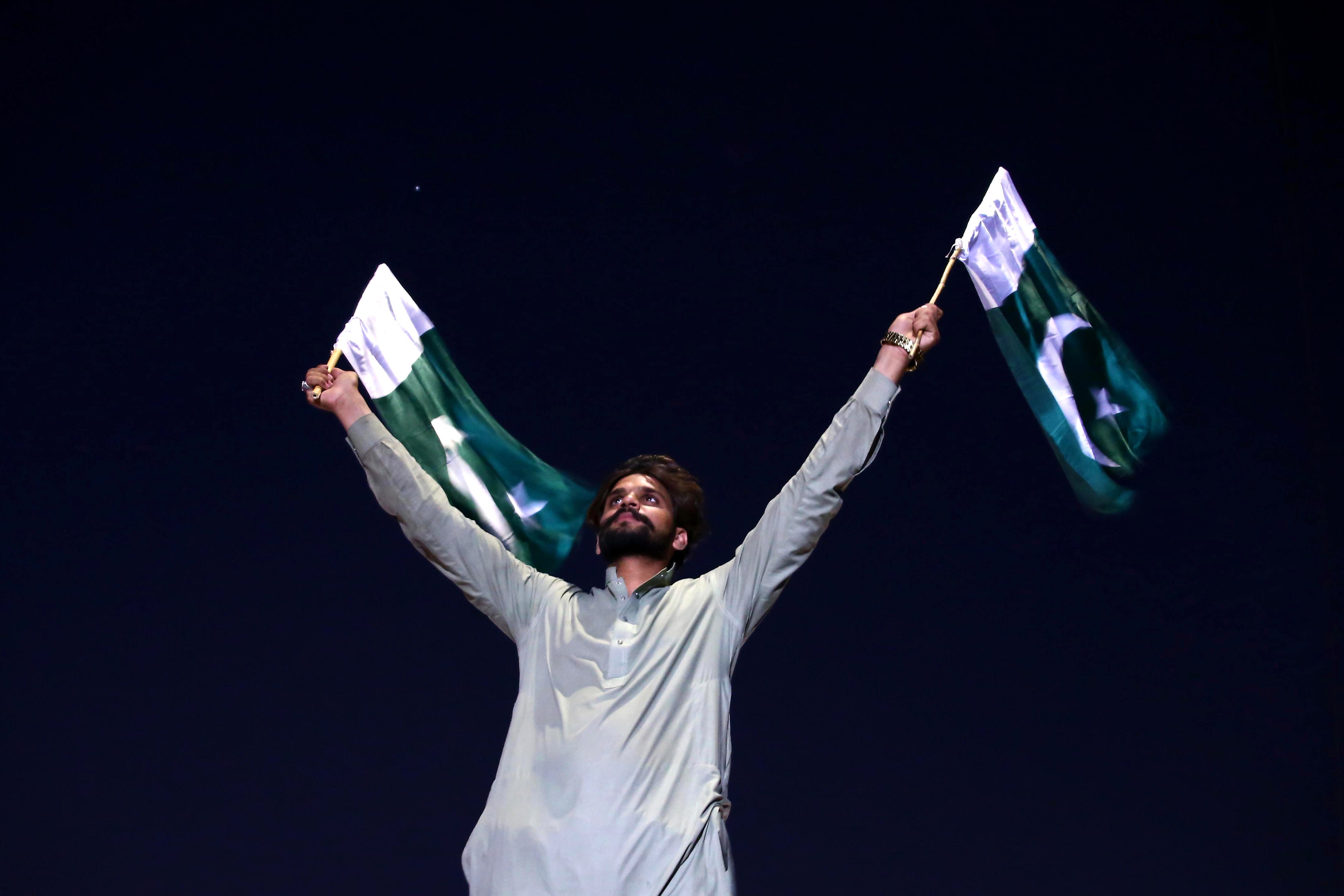 A Pakistani man waves national flags while celebrating the ceasefire agreed between Pakistan and India