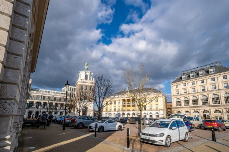 Poundbury, UK. 28 February 2025. Queen Mother Square in Poundbury near Dorchester with parked cars.