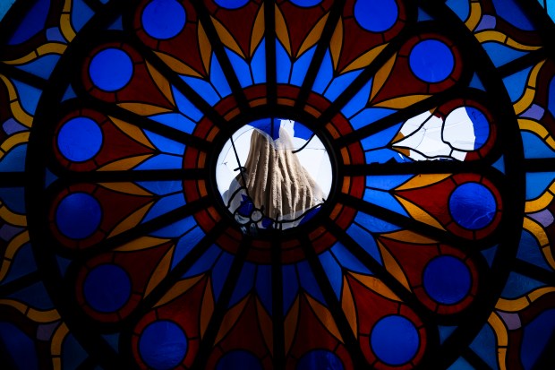 A statue of the Virgin Mary is seen through broken...