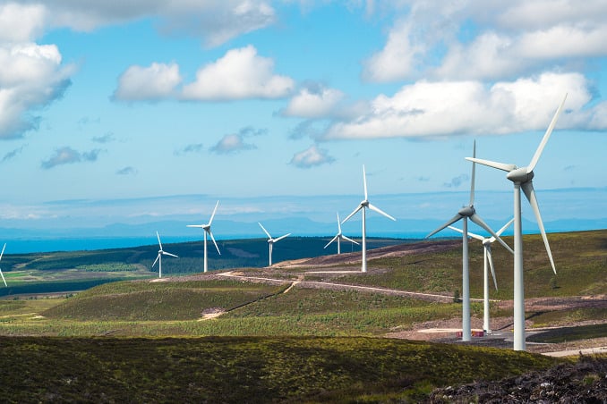 Wind turbines on brown hills under a blue sky