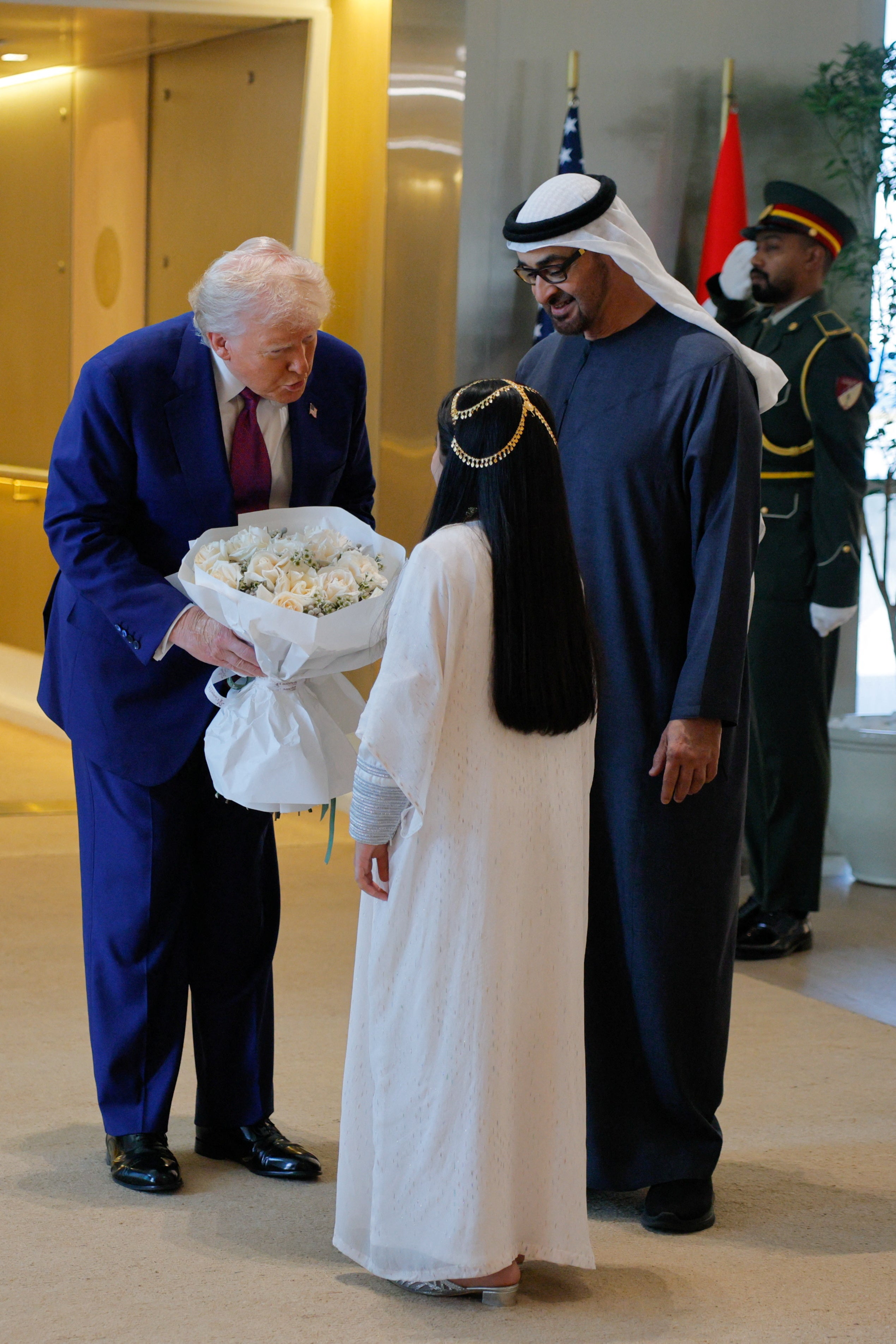 Trump receives flowers from a child next to United Arab Emirates President