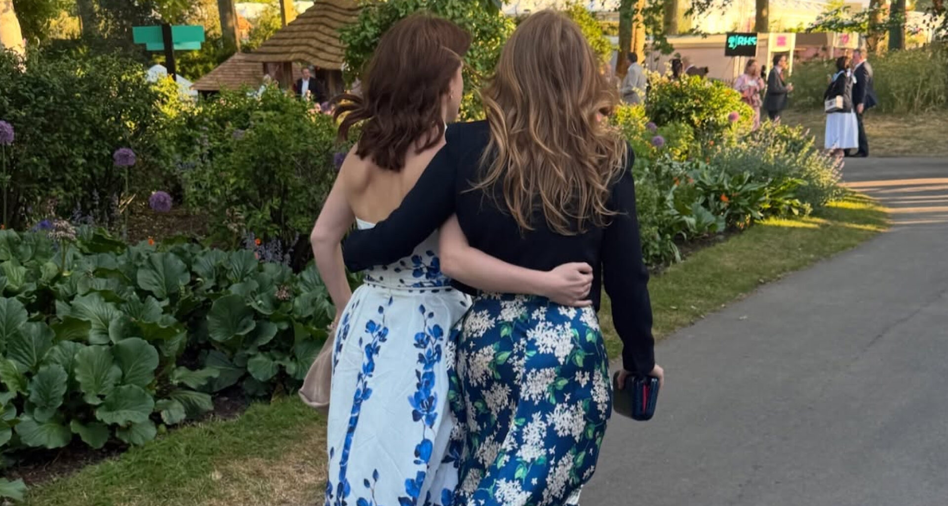 Princess Beatrice and Princess Eugenie walking with their arms around each other at the Chelsea Flower Show