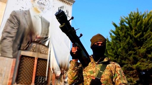 A rebel fighter posing in front of a defaced portrait ofBashar al-Assad in Damascus on Sunday. The Syrian government of Assad fell early Sunday, bringing an end to the 50-year rule of the Assad and his family. (Image: AFP)