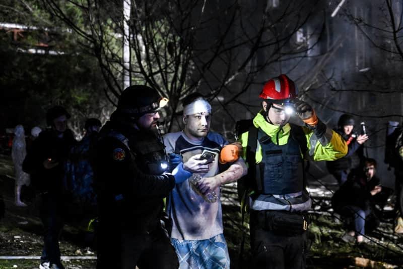 First responders help a man with a bandaged head outside an apartment block damaged by a large-scale Russian drone attack in Zaporizhzhia. Dmytro Smolienko/Ukrinform/dpa