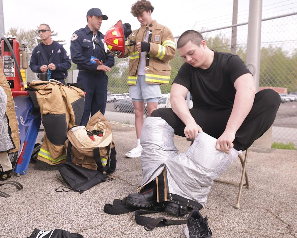 Joey Benson, a Fairless 11th grader, seated, and Bronson Brown, a Fairless freshman, try on Marathon Petroleum firefighter Ron DiFrancesco’s turnout gear during Career Day at Marathon Petroleum's Canton site.