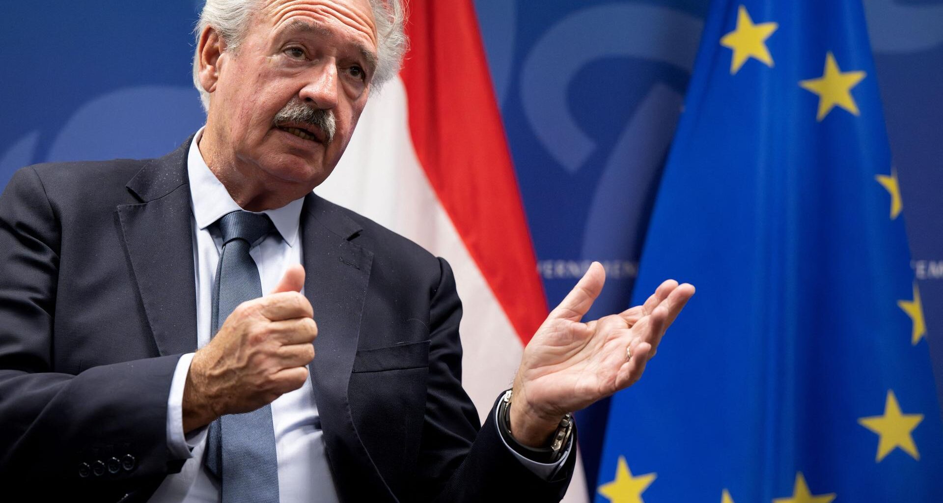 Das Foto zeigt den früheren luxemburgischer Außenminister Jean Asselborn. Er gibt ein Interview und hält seine Hände nach vorne.