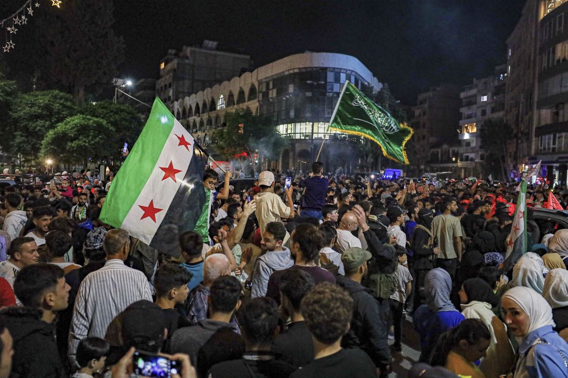 Syrians wave Saudi and Syrian flags in celebration after President Donald Trump announced plans during his visit to Saudi Arabia to ease sanctions on Syria and normalize relations with its new government, in Homs, Syria, on May 13.