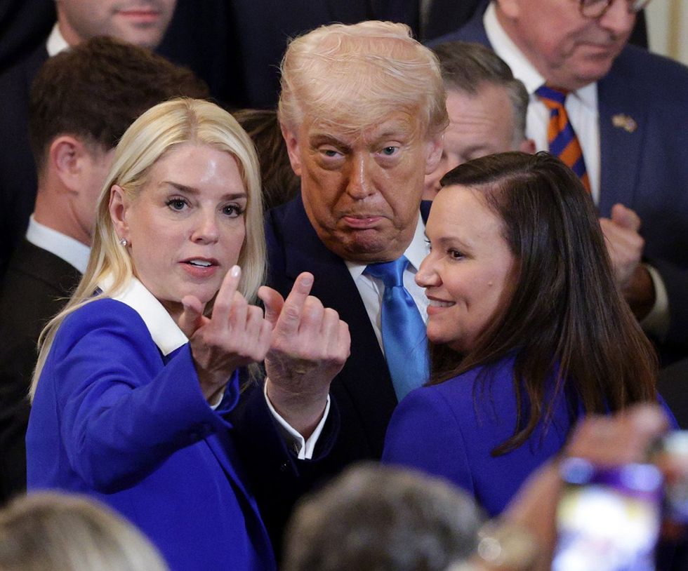 Attorney General Pam Bondi and President Donald Trump gesture toward the camera in a crowded room