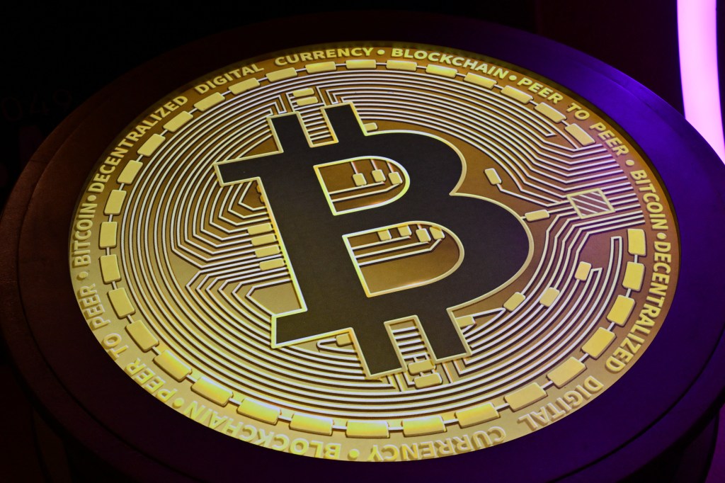 Bitcoin logo is displayed during token conference.