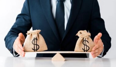 Businessman using his hands to balance a scale with a bag of money on each side