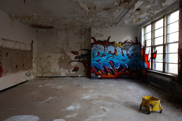 Graffiti covers a portion of a classroom wall in the...